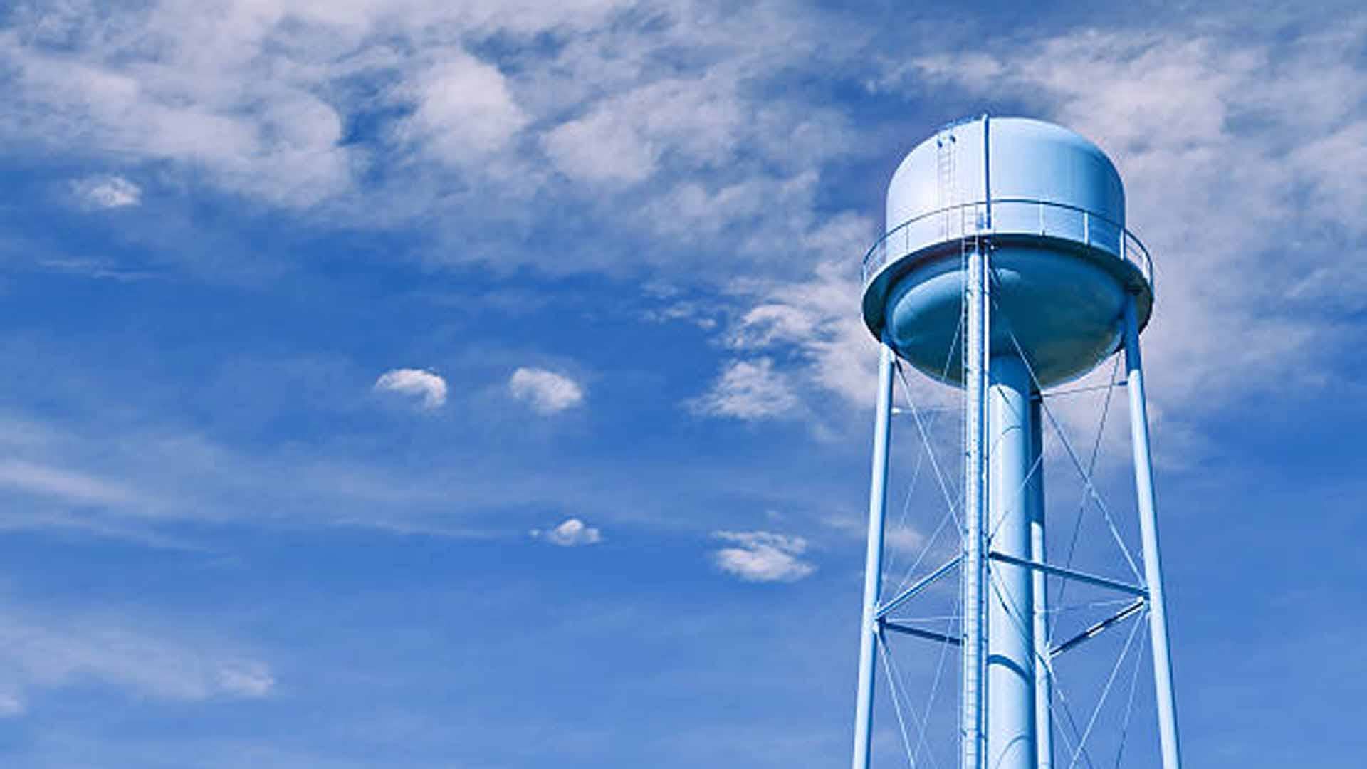 A city water tower set against a blue sky